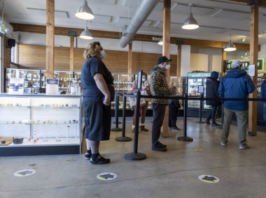 Woodinville, WA USA - Aralık 2021: Coronavirus salgını sırasında High Leaf esrar dükkanında sırada bekleyen müşterilere bakmak.