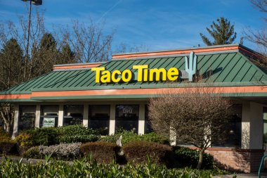 Woodinville, WA USA - Şubat 2022: Şehir merkezinde güneşli bir günde bir Taco Time fast food restoranının sokak manzarası.