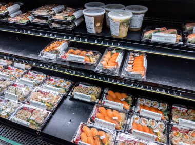 Kirkland, WA USA - Şubat 2022: Whole Foods 'un hazırlanmış gıda bölümünde önceden paketlenmiş suşinin açılı görünümü farklılık göstermektedir