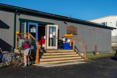 Cuma Limanı, WA USA - Kasım 2021: Parlak, güneşli bir günde bisikletini San Juan Adası Gıda Kooperatifi 'nin önüne park eden bir adamın açısı.