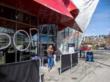 Seattle, WA USA - yaklaşık Mart 2022: Parlak, güneşli bir günde Pop Kültür Müzesine bebekli bir bebek arabasıyla giren aile.