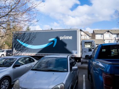 Seattle, WA USA - Mart 2022: Aydınlık, güneşli bir günde bir apartmanın dışındaki büyük bir Amazon Prime yarı kamyonunun açılı görüntüsü.
