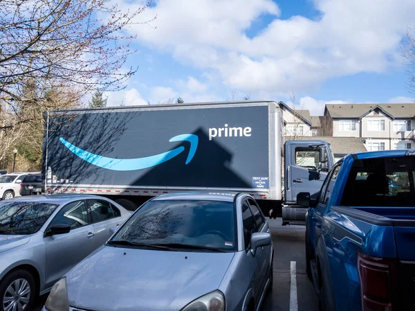 Seattle, WA USA - Mart 2022: Aydınlık, güneşli bir günde bir apartmanın dışındaki büyük bir Amazon Prime yarı kamyonunun açılı görüntüsü.