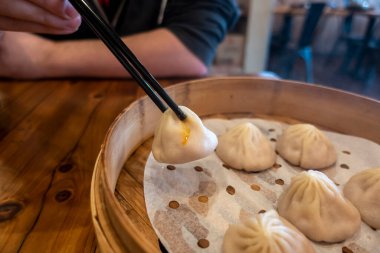 Xiao Long Bao 'yu bir restoranın içinde bir sepetten alan adamın yakın görüntüsü.