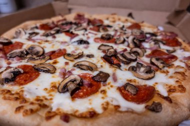 Makro, karton kutunun içinde taze mantar ve pepperoniyle kaplı peynirli pizzaya odaklan.