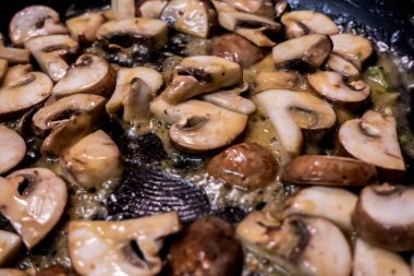 Macro, koca bir tavada pişen bebek Bella mantarlarına odaklan.