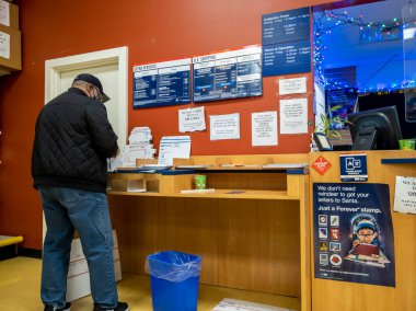 Kirkland, WA USA - Aralık 2021: Bayram sezonu boyunca USPS 'de paket taşıyan bir kişinin açılı görüşü