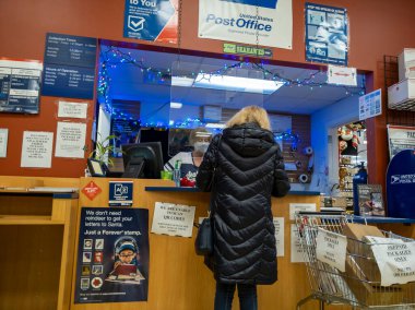 Kirkland, WA USA - Aralık 2021: Bayram sezonu boyunca USPS 'de paket taşıyan bir kişinin açılı görüşü