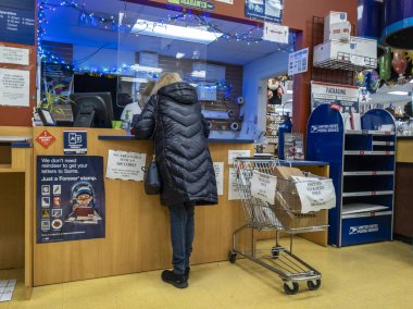 Kirkland, WA USA - Aralık 2021: Bayram sezonu boyunca USPS 'de paket taşıyan bir kişinin açılı görüşü.