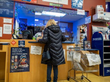 Kirkland, WA USA - Aralık 2021: Bayram sezonu boyunca USPS 'de paket taşıyan bir kişinin açılı görüşü