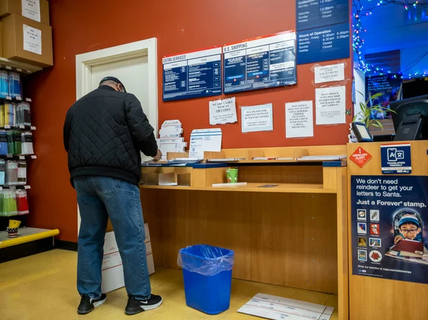 Kirkland, WA USA - Aralık 2021: Bayram sezonu boyunca USPS 'de paket taşıyan bir kişinin açılı görüşü
