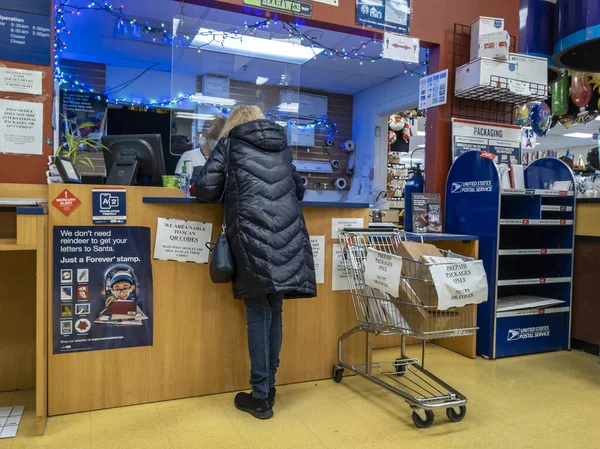 Kirkland, WA USA - Aralık 2021: Bayram sezonu boyunca USPS 'de paket taşıyan bir kişinin açılı görüşü.