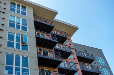 Güneşli ve bulutlu bir günde bir sürü penceresi olan modern bir iş binasının düşük açılı görüntüsü