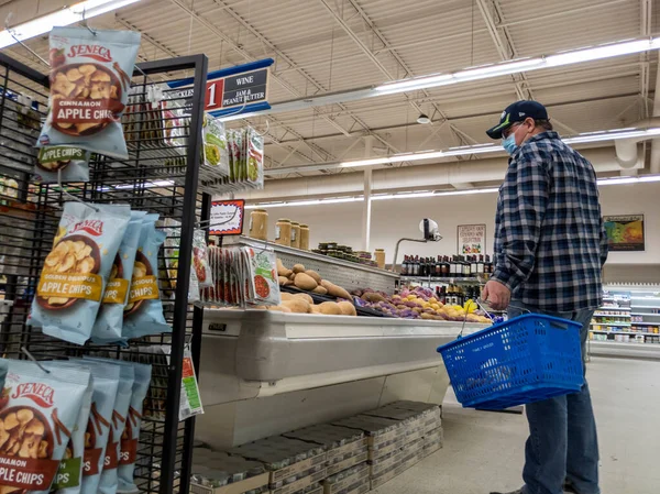 Gold Bar, WA USA - Ocak 2022: Gold Bar Family Grocer 'da yüz maskesi takmış yaşlı bir adamın patates alışverişi yaparken düşük açılı görüntüsü.