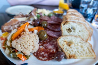 Restorandaki ahşap bir masada şarküteri tabağında bol bol yiyecek seçimi.