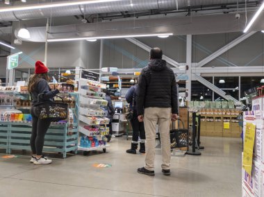 Kirkland, WA USA - Nisan 2022: Whole Foods 'daki bir markette kendi kendini kontrol eden kadın ve erkeklerin kuyruğa girmesi.