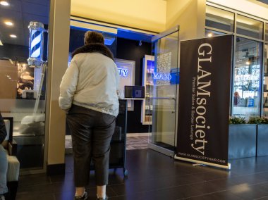 Bellevue, WA USA - Nisan 2022: GLAMsociety kuaför salonunda kendini kontrol eden bir kadının görüntüsü..