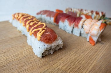 Bambu kesme tahtasındaki çeşitli suşi rulolarının açılı, seçici odak görünümü