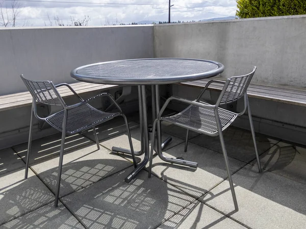 Yuvarlak, metal bir masası ve iki sandalyesi olan, Bellevue, WA şehir merkezine bakan bir çatı balkonu manzarası.