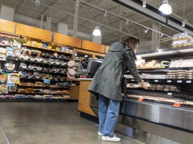 Lynnwood, WA USA - Mart 2022: Bir kasaba ve ülke marketinde orta yaşlı bir kadının pasta ve kek alışverişi yapması.