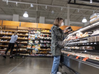 Lynnwood, WA USA - Mart 2022: Bir kasaba ve ülke marketinde orta yaşlı bir kadının pasta ve kek alışverişi yapması