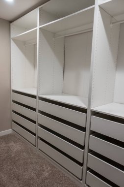 Uzun, beyaz dolaplar ve çekmeceler ana yatak odasındaki dolap içinde dar bir yürüyüş.