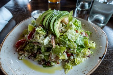 Lüks bir restoranda beyaz ve altın tabakta bozulmuş Dungeness yengeci ve avokado salatası.
