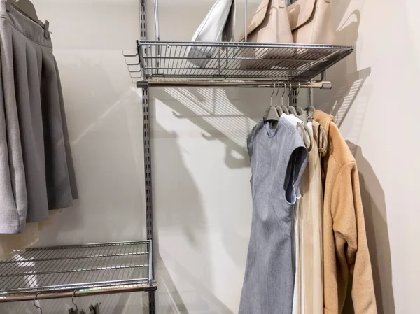 Collection of monotone colors tops and bottoms hanging inside an organized walk in closet with metal wire rack shelving