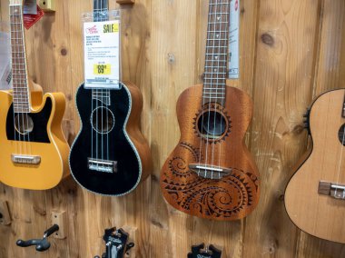 Lynnwood, WA USA - circa May 2022: Close up, selective focus on ukuleles for sale on the wall inside a Guitar Center musical instrument store.