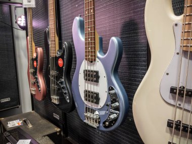 Lynnwood, WA USA - circa May 2022: Selective focus on electric and acoustic bass guitars for sale inside a Guitar Center musical instrument store.