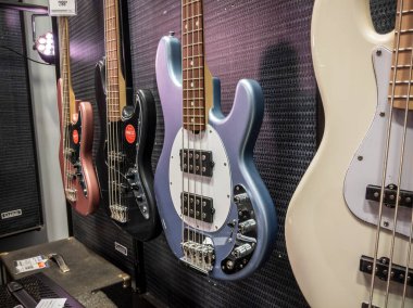 Lynnwood, WA USA - circa May 2022: Selective focus on electric and acoustic bass guitars for sale inside a Guitar Center musical instrument store. clipart