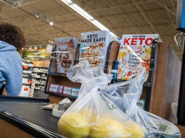 Mill Creek, WA USA - circa April 2022: Angled view of a customer placing bagged produce on a conveyor belt to be purchased inside a Town and Country grocery store