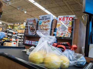Mill Creek, WA USA - circa April 2022: Angled view of a customer placing bagged produce on a conveyor belt to be purchased inside a Town and Country grocery store