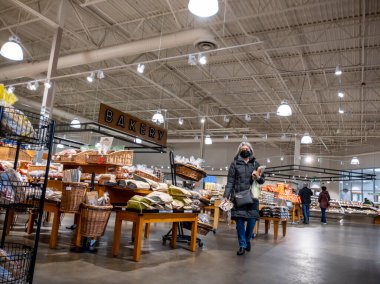 Mill Creek, WA USA - circa April 2022: View of an elderly woman carrying groceries through the bakery section of a Town and Country grocery store