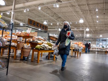 Mill Creek, WA USA - circa April 2022: View of an elderly woman carrying groceries through the bakery section of a Town and Country grocery store.