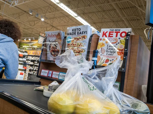 Mill Creek, WA USA - Nisan 2022: Bir kasaba ve ülke marketinden satın alınmak üzere poşetlenmiş ürünleri bir taşıma bandına yerleştiren bir müşterinin açılı görünümü