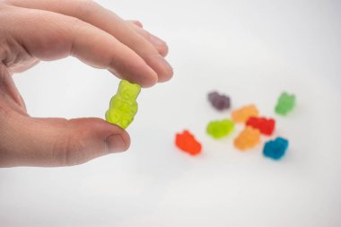 Renkli bir CBD 'yi elinde tutan bir erkeğin görüntüsü şifalı şeker jelibonu.