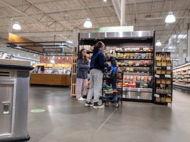 Lynnwood, WA USA - Mart 2022: Bir kasaba ve ülke pazarı içinde humus ve salsa sosu etrafında alışveriş yapan bir ailenin görüntüsü.