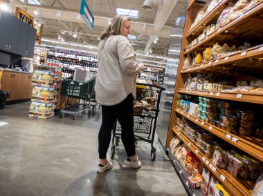 Mill Creek, WA USA - Mayıs 2022: Bir kasaba ve kasaba bakkalının fırın bölümünün pide ekmek ve tortilla bölümünde alışveriş yapan yaşlı bir kadının görüntüsü
