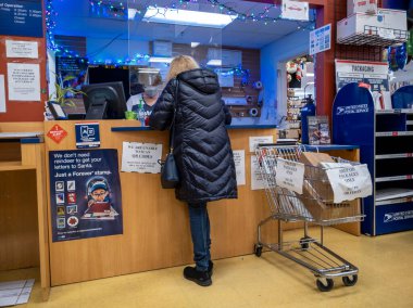 Kirkland, WA USA - Aralık 2021: Bayram sezonu boyunca USPS 'de paket taşıyan bir kişinin açılı görüşü