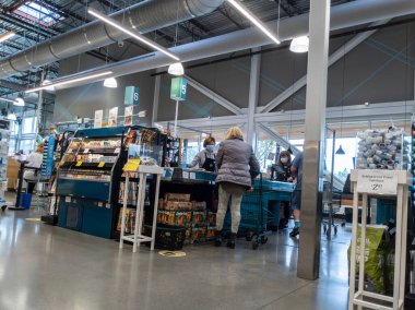 Kirkland, WA USA - Eylül 2021: Whole Foods Market 'in içinde yüz maskesi takan bir kasiyerle çıkış yapan bir kadının açısı.