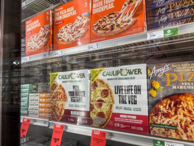 Mill Creek, WA USA - Mayıs 2022: Bir kasaba ve ülke pazarının dondurucu bölümünde satılık çeşitli dondurulmuş pizzaların açılı görünümü.
