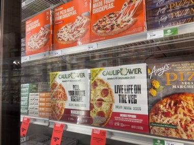 Mill Creek, WA USA - Mayıs 2022: Bir kasaba ve ülke pazarının dondurucu bölümünde satılık çeşitli dondurulmuş pizzaların açılı görünümü.