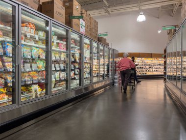 Mill Creek, WA USA - Mayıs 2022: Bir kasaba ve ülke pazarının donmuş gıda reyonunda pembe kapüşonlu yaşlı bir kadının bakış açısı