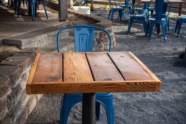 Colorful view of bright blue chairs gathered around a wooden table on an outdoor patio at a restaurant