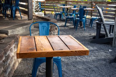 Colorful view of bright blue chairs gathered around a wooden table on an outdoor patio at a restaurant