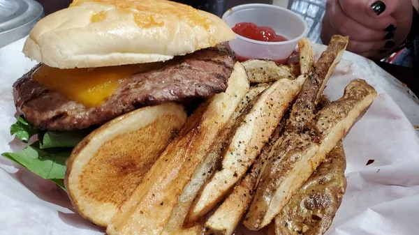 Yağlı bir çizburger ve çıtır bir biftek kızartması manzarası var, yerel bir hamburgercide servis edilen bir sepette.