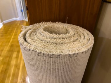 Yuvarlanmış, eski bir halının ahşap bir kitaplığa yaslanmış görüntüsü.