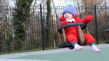 Küçük kız parkta salıncakta eğleniyor.