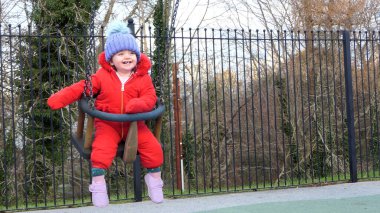 Küçük kız parkta salıncakta eğleniyor.